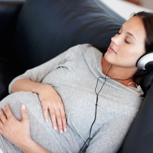 Fun Gender Reveal Ideas Pregnant Woman Sitting Down Listening to Music Holding Belly