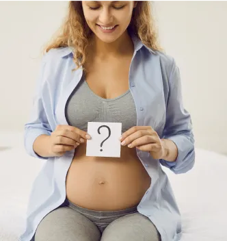 Expectant mother holding a question-mark card while awaiting NIPT gender results